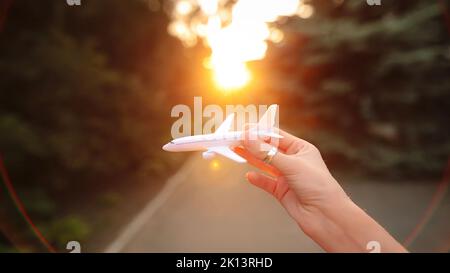 Female hand simulates a flight with plastic airplane in the evening. Stock Photo