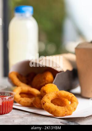 Crunchy deep fried squid or onion rings in batter set on gray stone table background. Co Stock Photo
