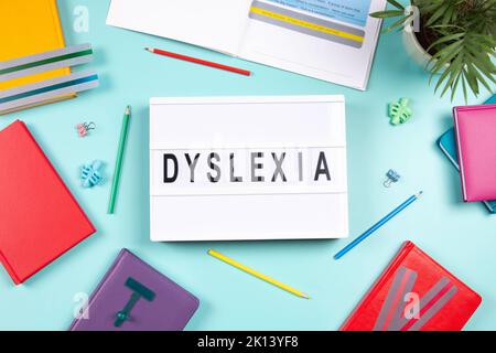 Dyslexia awareness, help children with reading, learning difficulties concept. Lightbox with DYSLEXIA word, colorful books and open book with reading Stock Photo