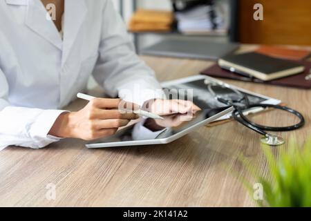 Cropped of female doctor using gadgets at workplace, holding smartphone and digital tablet. Unrecognizable therapist having online conversation with Stock Photo
