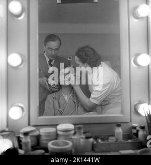 Make-up in the 1950s. Prior her going on the filmset, actress Maj-Britt Nilsson gets a theatrical makeup done by an assistant. Note the photographer in the mirror adding himself into the picture. Sweden 1953 Kristoffersson ref BL42-3 Stock Photo