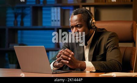 Office worker in headphones communicates with client on headset on laptop male psychologist talking to patient via video call at online conference Stock Photo