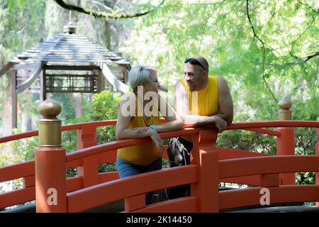 Young couple laughing while standing in the park on bridge Stock Photo