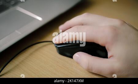 Hand of young caucasian man clicking and scrolling mouse Stock Photo