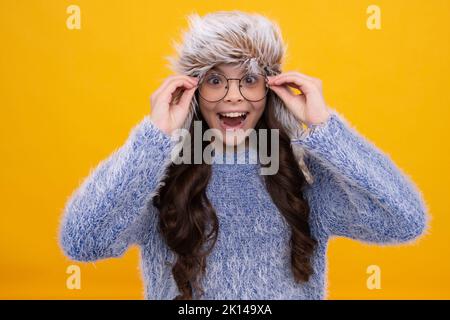 Fashion happy young woman in knitted hat and sweater having fun over colorful blue background Excited face, cheerful emotions of teenager girl. Stock Photo