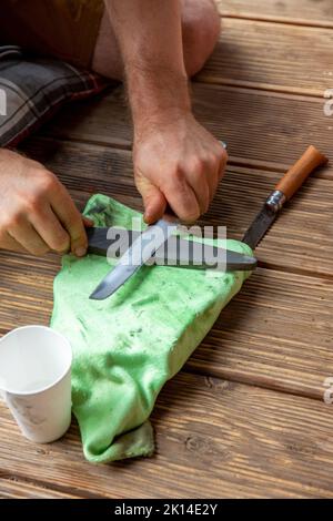 Man Sharpening Knife With A Whetstone Stock Photo