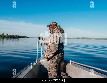 Tatarstan, Russia. August 19, 2022. Environmental police officer in a raid to apprehend poachers. A man in camouflage on the bow of a boat.  Stock Photo