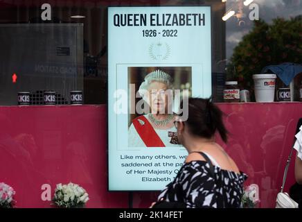 London, UK. 15th Sep, 2022. A woman looks at a photograph of the recently deceased Queen Elizabeth II at a shop on Oxford Street during the wake days in London. Credit: SOPA Images Limited/Alamy Live News Stock Photo