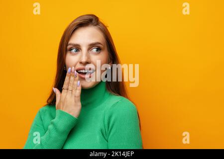 Photo of beautiful woman holding hands near mouth against yellow background Stock Photo