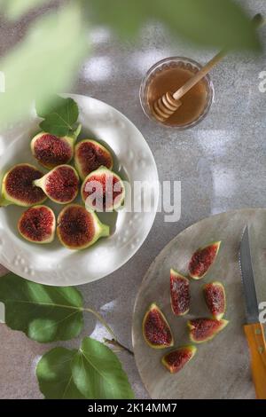 Plate with fresh green figs on plate and honey on gray background. Stock Photo