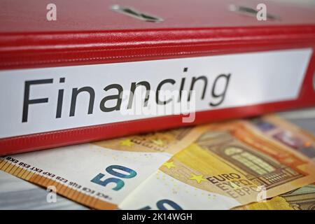 Closeup of isolated red file folder with word financing, euro money banknotes Stock Photo