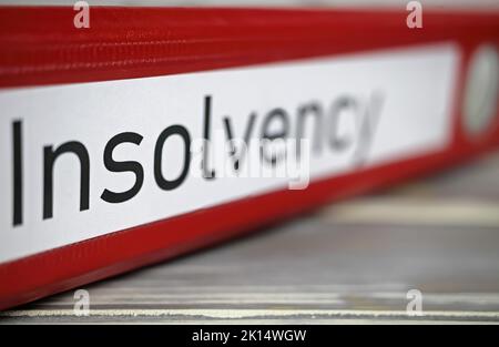 Closeup of isolated red file folder with english word insolvency on wood table (selective focus on center of letter S) Stock Photo
