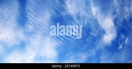 Isolated beautiful clear blue summer sky cloudscape with different shapes blurred washed out wind blown cirrus clouds, stratus stripes and floccus tuf Stock Photo