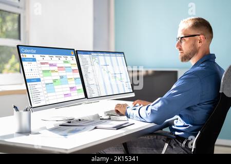 Employee Working On Calendar Schedule And Staff Time Sheet Stock Photo