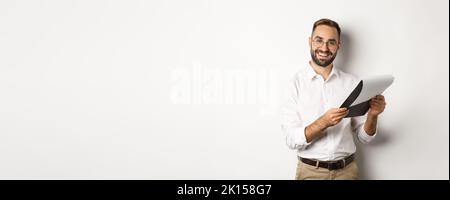 Employer looking satisfied at CV, reading document and smiling, standing over white background Stock Photo