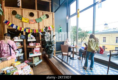 St. Petersburg, Russia, August 2021: Workplaces near a huge window in childrens department of a bookstore. Women and girl inside. Stock Photo