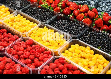 Colourful mix of different fresh berries at market. Raspberries, strawberries, blueberries and bilberries Stock Photo