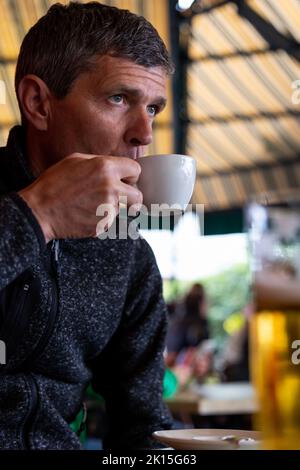 Portrait of serious mature man drinking coffee in cafe and seems worried Stock Photo