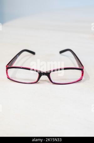 Pair of purple women's single vision reading glasses, or spectacles lying on a white background. Stock Photo