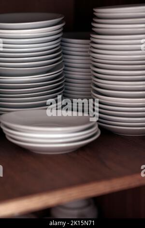 Stacks of clean white plates on shelf. Close up Stock Photo