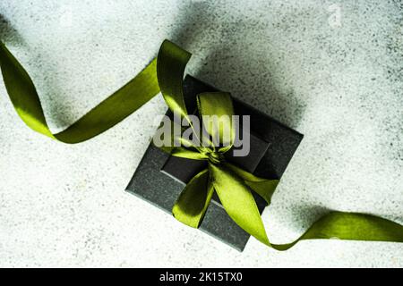 From above gift box decorated with bright green ribbon on concrete background Stock Photo