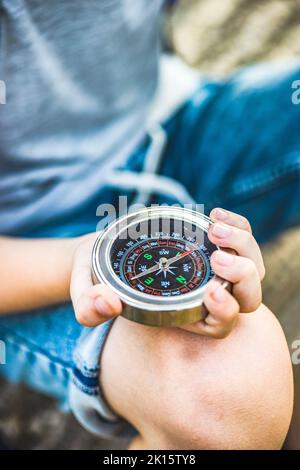 From above cropped unrecognizable boy in the straw hat with compass in summer Stock Photo