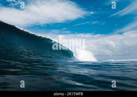 Powerful foamy sea waves rolling and splashing over water surface against cloudy blue sky in Thulusdhoo Island in Maldives Stock Photo