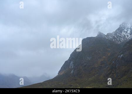 Range of rough rocky mountains with uneven surface covered with snow located against overcast cloudy sky in nature on winter day in Lofoten, Norway Stock Photo