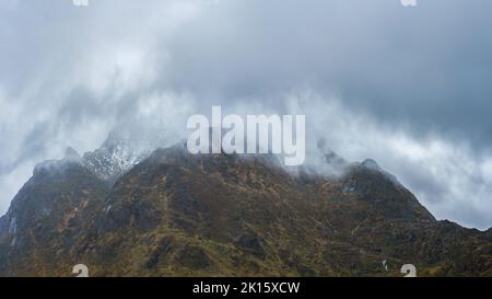 Range of rough rocky mountains with uneven surface covered with snow located against overcast cloudy sky in nature on winter day in Lofoten, Norway Stock Photo