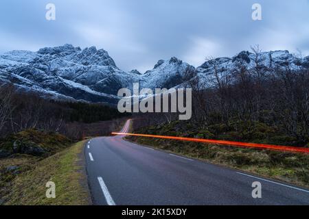 Scenic view of automobile driving on mountainous road in winter under cloudy sky in Norway Stock Photo