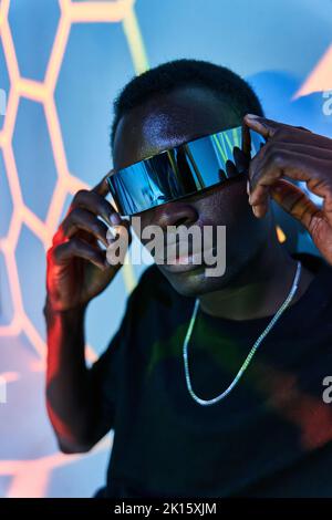 Concentrated young African American male millennial in casual clothes and VR glasses looking at camera against colorful background Stock Photo