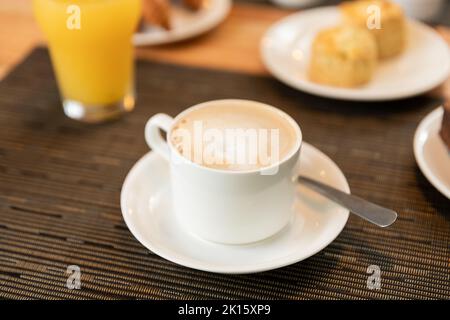 Top view of cup of latte placed on saucer with spoon on table during breakfast in cafeteria Stock Photo