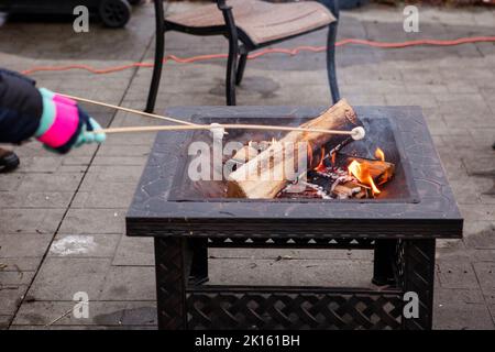 close-up of two children roasting marshmallows in winter over fire pit Stock Photo