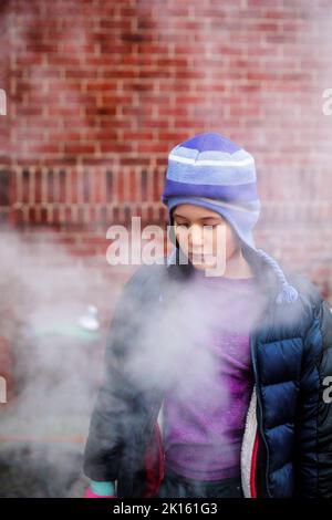 A beautiful serious child standing in smoke gazes down Stock Photo