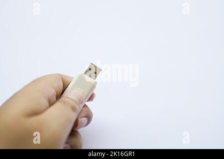 human hand on used flash drive is white, Compact USB drive, Close-up of flash memory template isolated on white. Stock Photo