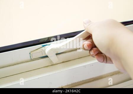 human hand on plastic window lock handle Stock Photo