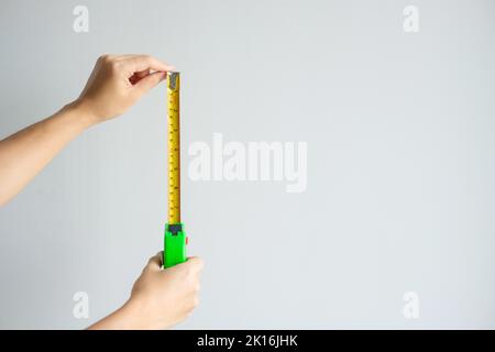 Man hand using tape measure for measuring with wall backgrounds at home. DIY, Interior design, repairing and improvement home or apartment concepts Stock Photo