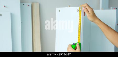 Man hand using tape measure for measuring furniture at home. DIY, Interior design, repairing and improvement home or apartment concepts Stock Photo
