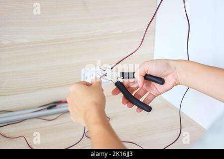 Electrician cuts electrical wires with pliers, Wiring cables installation for socket plug. Fixing, Renovation, Repair, service and development of home Stock Photo