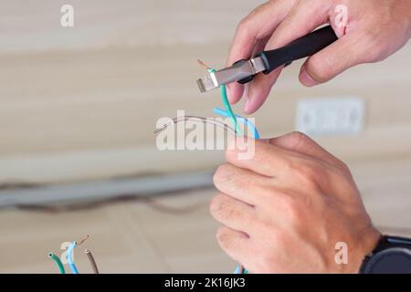 Electrician cuts electrical wires with pliers, Wiring cables installation for socket plug. Fixing, Renovation, Repair, service and development of home Stock Photo