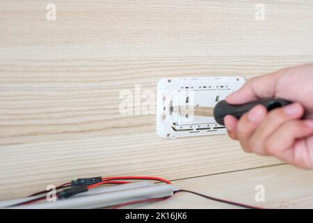 Man hand using screwdriver installing Wire cables for socket plug. Renovation, Repair, fixing and development of home and apartment concepts Stock Photo