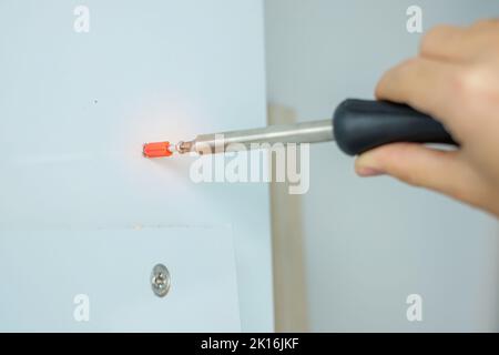 man using screwdriver assembling or repairing furniture at home. DIY, Renovation, repairing and development home or apartment concepts Stock Photo