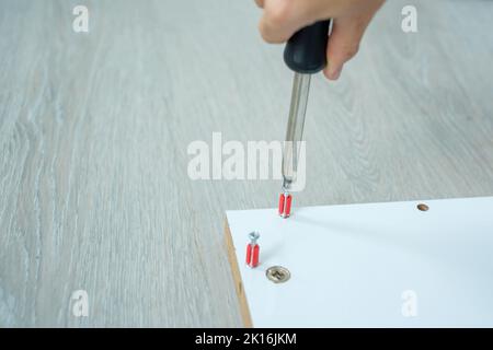 man using screwdriver assembling or repairing furniture at home. DIY, Renovation, repairing and development home or apartment concepts Stock Photo