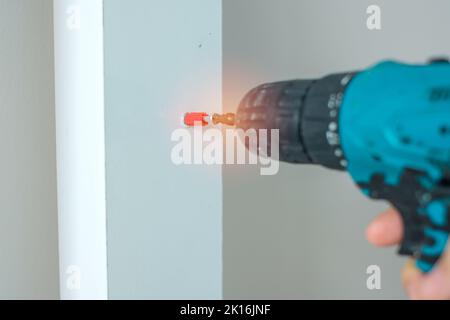 man using a cordless screwdriver assembling furniture at home, Carpenter working with electric screwdriver on the work Stock Photo