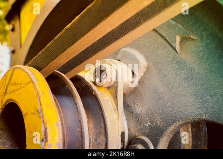 Corrosion in the grooves of the pulley. V-belt in the grooves. Drive belt old worn out on a yellow pulley, blurred background. Industrial items in agr Stock Photo