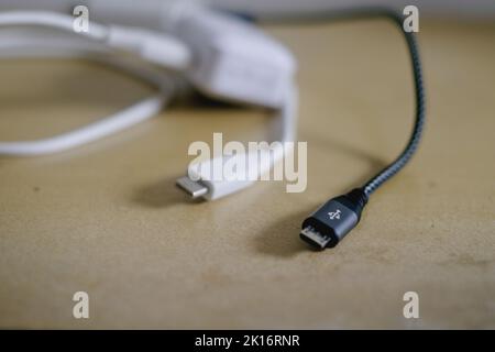 Black and white fast charging mobile phone chargers for Android phones with detachable USB to micro USB data cables on the table. Selective focus. Stock Photo