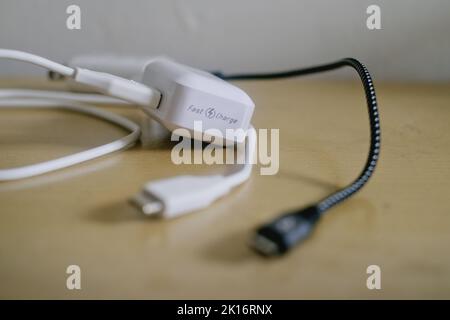 Black and white fast charging mobile phone chargers for Android phones with detachable USB to micro USB data cables on the table. Selective focus. Stock Photo