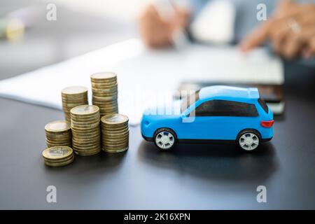 Blue Toy Car In Front Of Businesswoman Calculating Loan Stock Photo