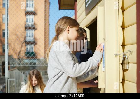 Girls looking through wooden building window Stock Photo