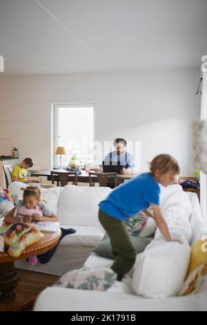 Children playing while father working from home Stock Photo